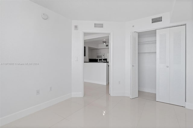 unfurnished bedroom featuring light tile patterned floors and a closet