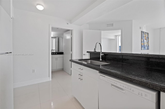 kitchen with light tile patterned flooring, white cabinetry, sink, white dishwasher, and dark stone countertops