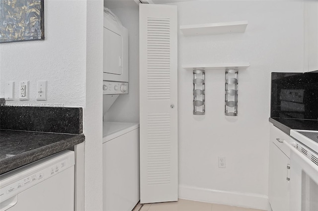 clothes washing area featuring stacked washing maching and dryer and light tile patterned floors