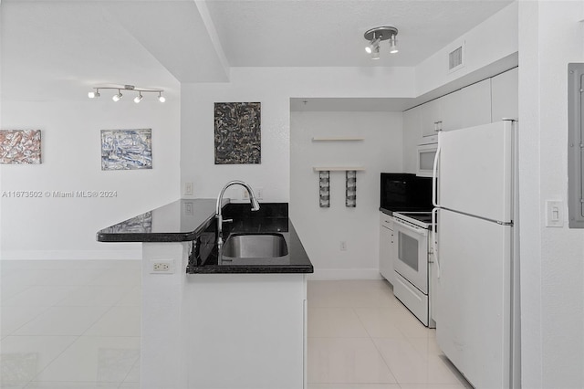 kitchen with kitchen peninsula, sink, light tile patterned floors, white cabinetry, and white appliances