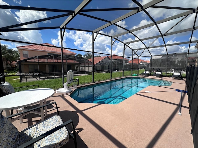 view of swimming pool featuring a lawn, a patio area, and a lanai