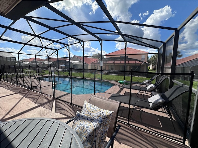 view of swimming pool featuring glass enclosure and a patio