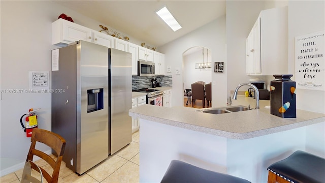 kitchen featuring stainless steel appliances, sink, kitchen peninsula, white cabinetry, and a kitchen bar