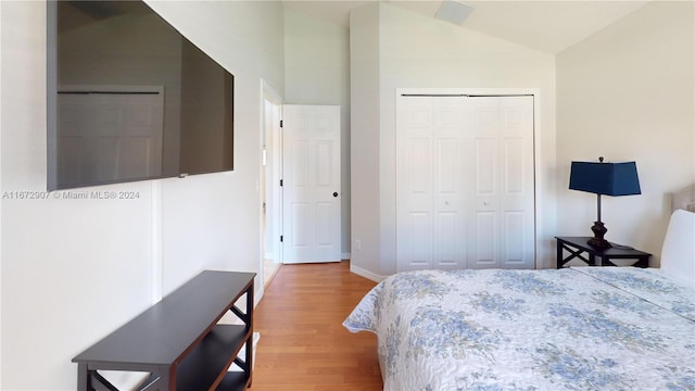 bedroom with lofted ceiling, a closet, and light wood-type flooring