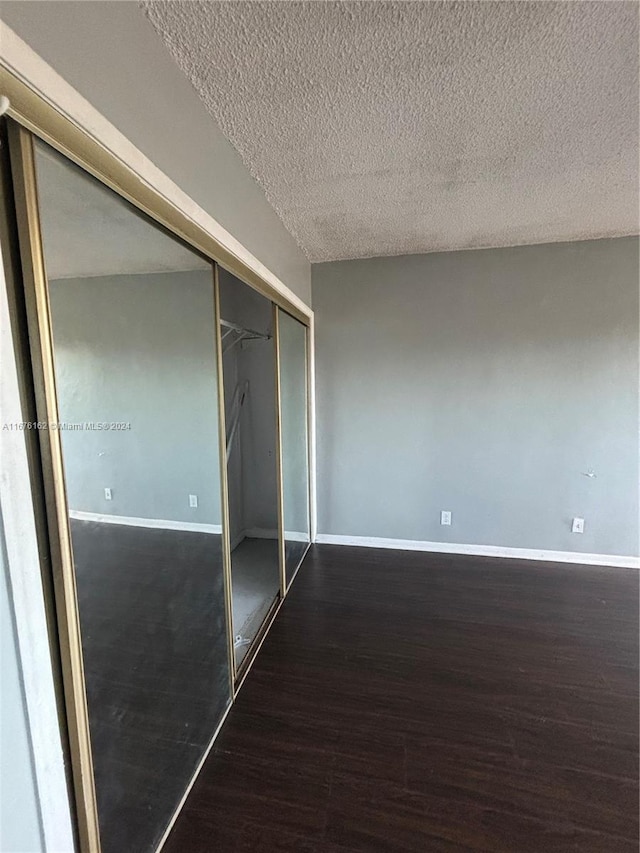 unfurnished bedroom featuring a closet, dark hardwood / wood-style floors, and a textured ceiling