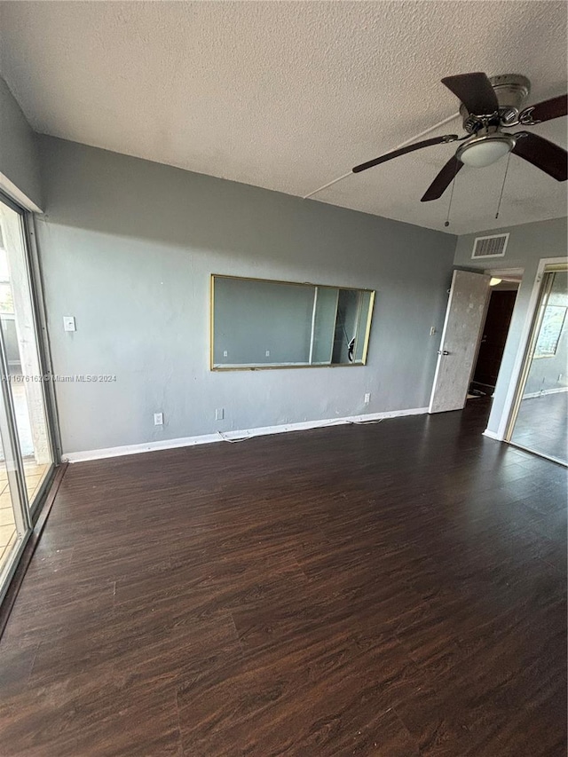 empty room featuring a textured ceiling, plenty of natural light, and dark hardwood / wood-style flooring