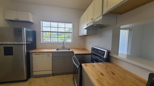 kitchen with light tile patterned floors, sink, gray cabinetry, appliances with stainless steel finishes, and wood counters