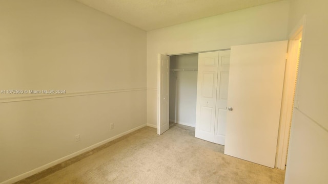 unfurnished bedroom featuring a closet and light carpet