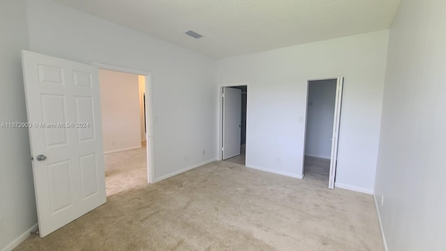 unfurnished bedroom with a spacious closet and light colored carpet