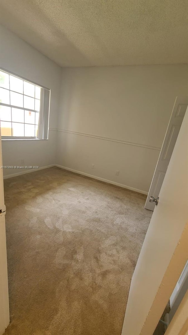 carpeted empty room featuring a textured ceiling