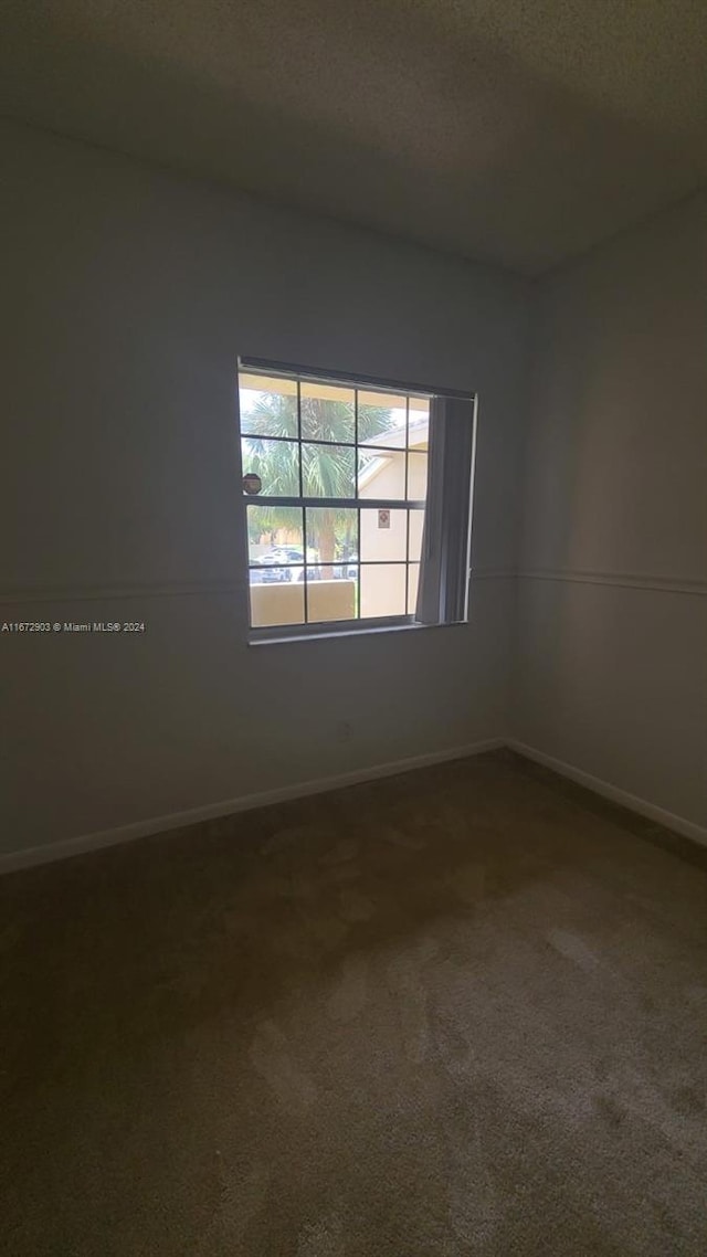 carpeted empty room featuring a textured ceiling