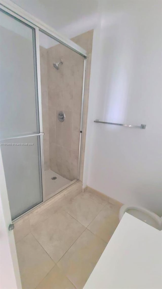 bathroom with a shower with shower door and tile patterned flooring