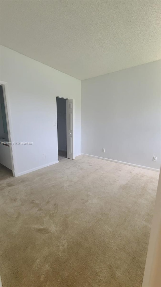 carpeted empty room featuring a textured ceiling