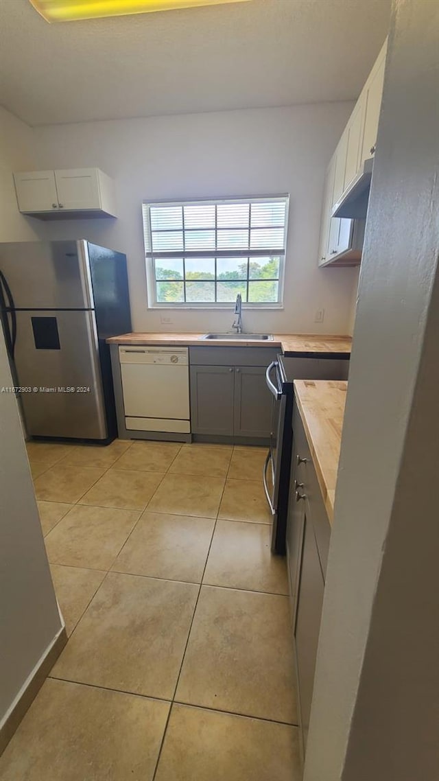 kitchen with gray cabinetry, sink, stainless steel appliances, white cabinets, and light tile patterned floors