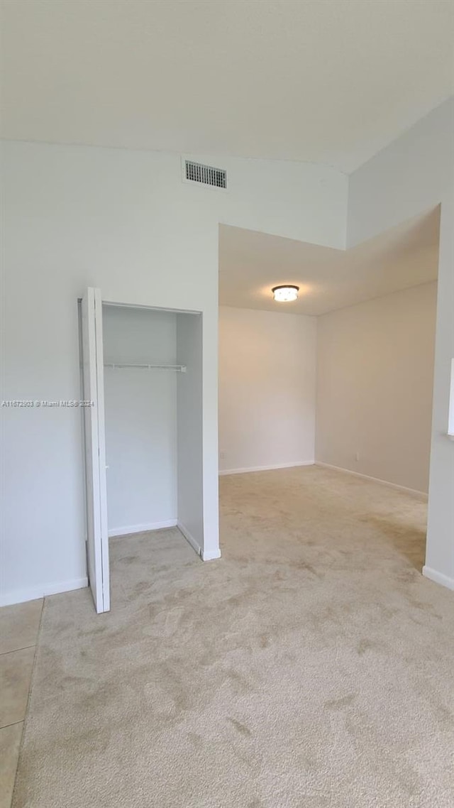 unfurnished bedroom featuring a closet and light colored carpet