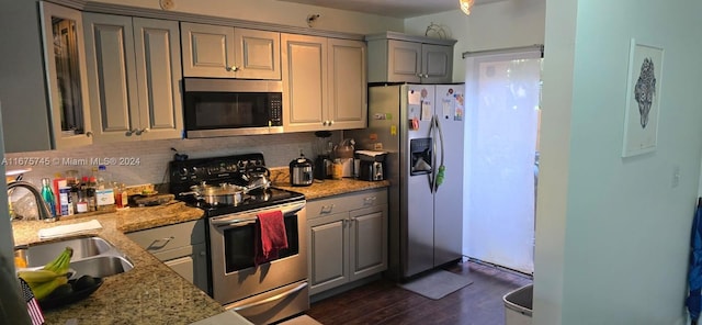 kitchen with light stone countertops, decorative backsplash, dark hardwood / wood-style floors, stainless steel appliances, and gray cabinets