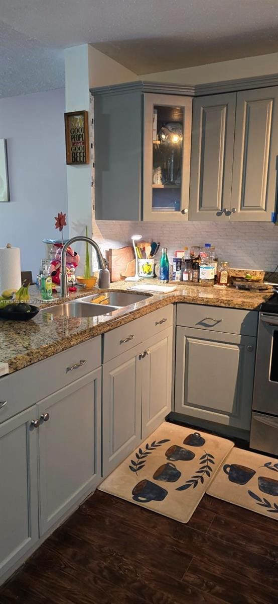 kitchen featuring light stone countertops, dark hardwood / wood-style floors, sink, stainless steel electric range oven, and backsplash