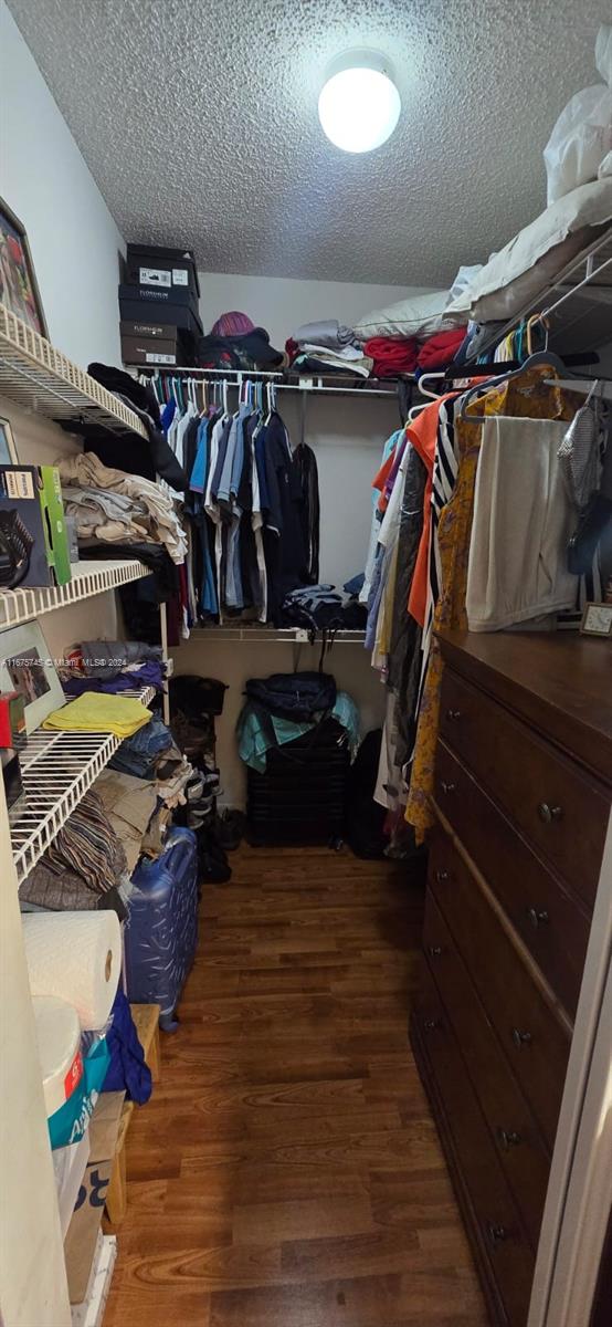 walk in closet with dark wood-type flooring