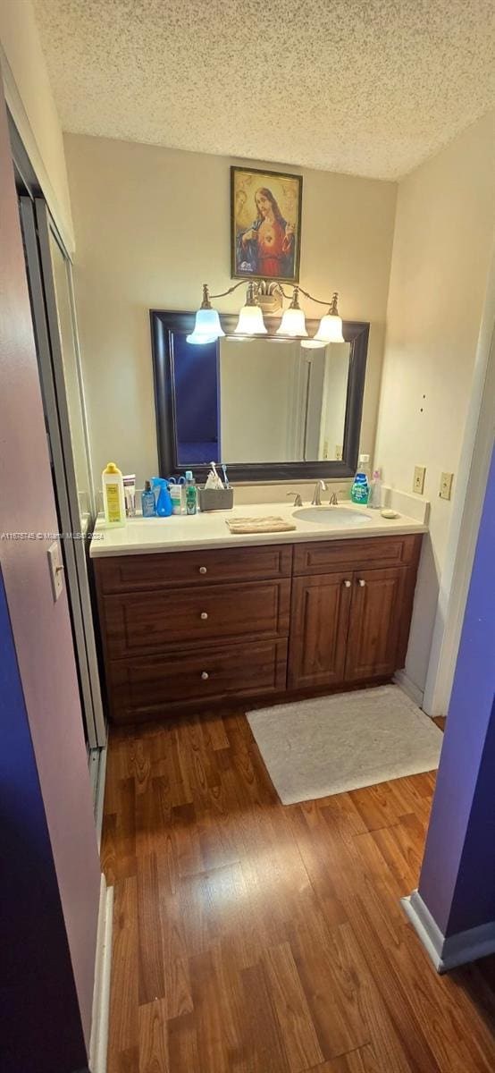 bathroom with an enclosed shower, hardwood / wood-style floors, vanity, and a textured ceiling