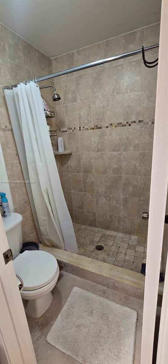 bathroom with tile patterned flooring, walk in shower, and toilet