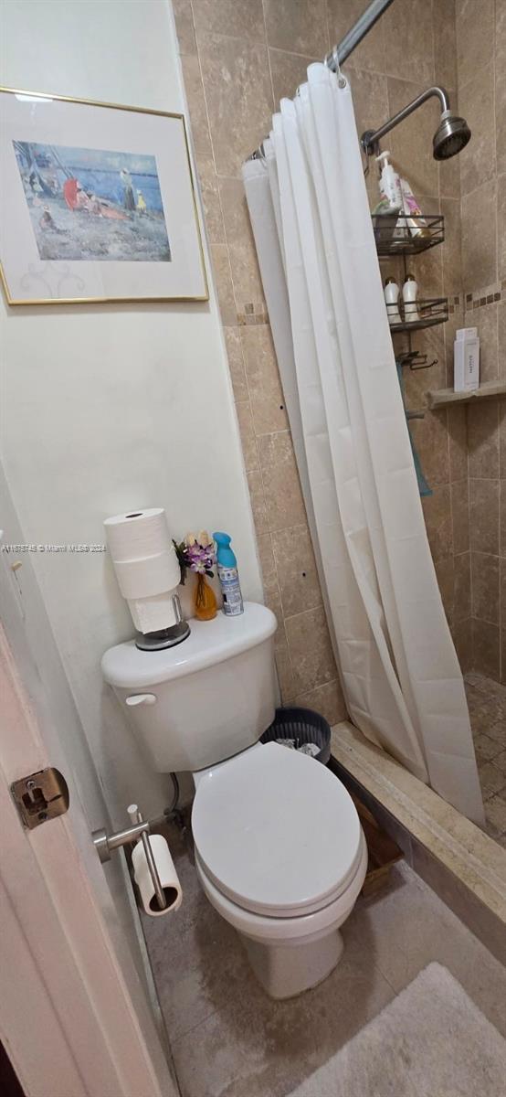 bathroom featuring toilet and curtained shower