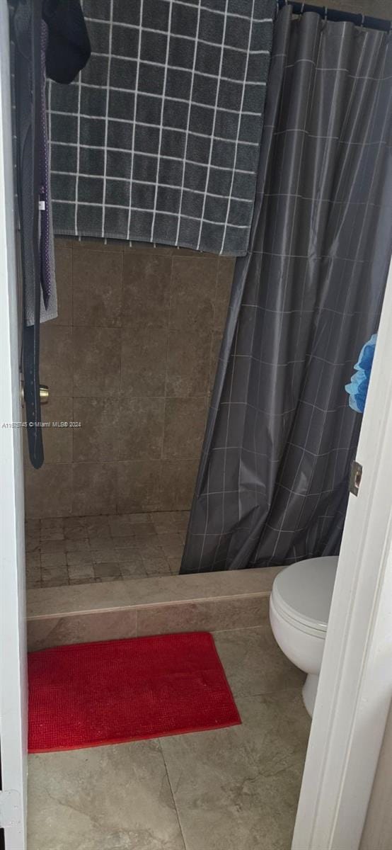 bathroom featuring tile patterned flooring, walk in shower, and toilet