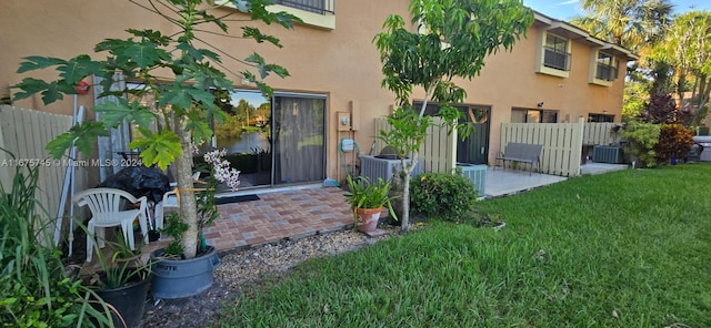 doorway to property featuring a patio, a lawn, and central AC unit