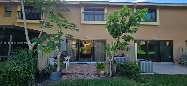 back of property featuring a balcony, a patio area, and central air condition unit