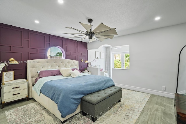 bedroom featuring ceiling fan, a textured ceiling, and light wood-type flooring