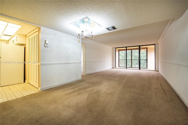 spare room featuring light colored carpet, an inviting chandelier, crown molding, and a textured ceiling