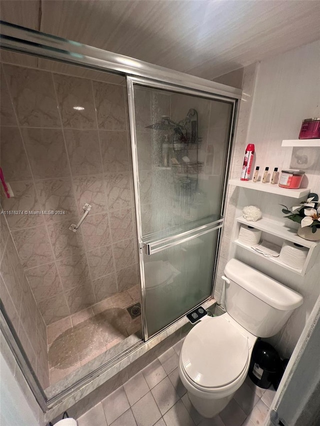 bathroom featuring a shower with shower door, toilet, and tile patterned floors