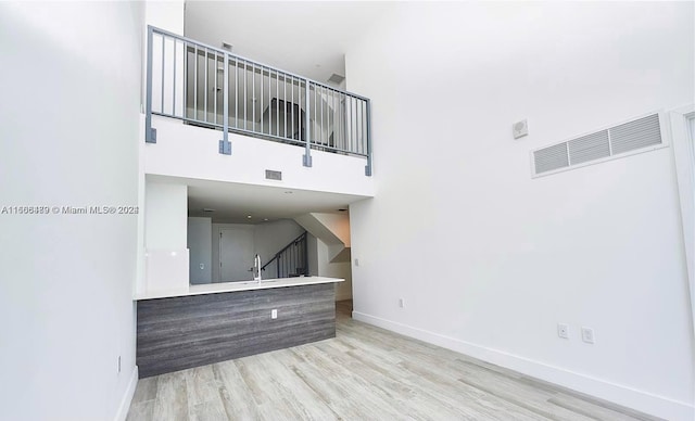 unfurnished living room with light hardwood / wood-style floors, a high ceiling, and sink