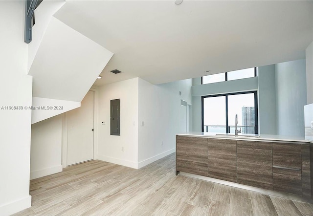 interior space with electric panel, light hardwood / wood-style flooring, and sink