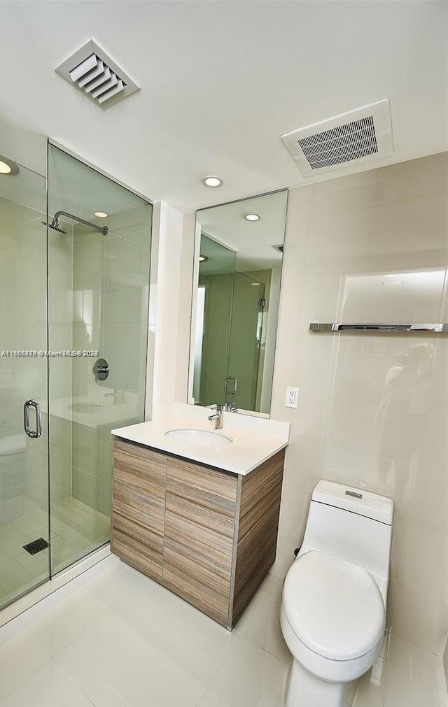 bathroom with tile patterned flooring, toilet, a shower with door, and vanity