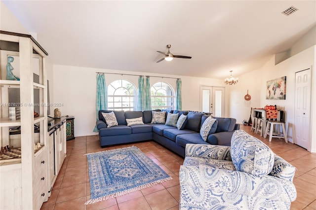 tiled living room with ceiling fan with notable chandelier