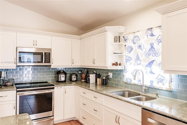 kitchen with appliances with stainless steel finishes, white cabinetry, vaulted ceiling, and backsplash