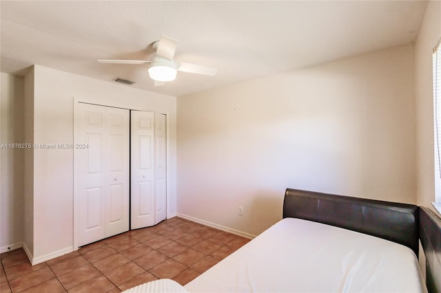 bedroom with a closet, light tile patterned floors, and ceiling fan