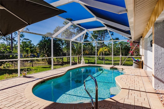 view of pool with a yard, glass enclosure, and a patio