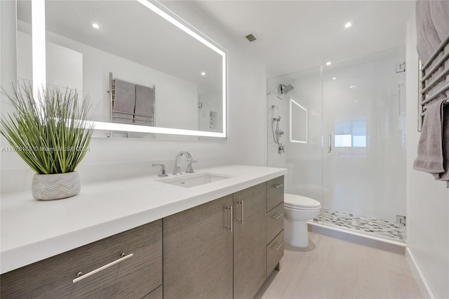 bathroom featuring wood-type flooring, vanity, toilet, and a shower with door