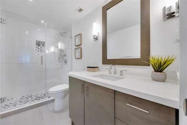 bathroom featuring a shower with shower door, vanity, and toilet