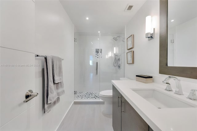 bathroom featuring vanity, toilet, and a shower with shower door