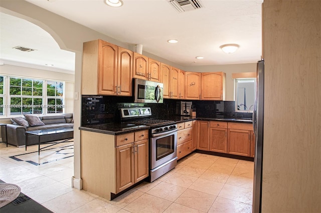 kitchen with light tile patterned floors, sink, ornamental molding, backsplash, and appliances with stainless steel finishes