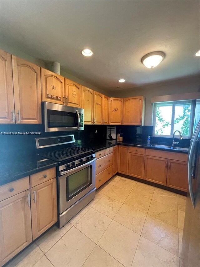 kitchen featuring recessed lighting, marble finish floor, a sink, stainless steel appliances, and backsplash