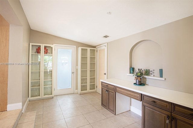interior space featuring light tile patterned floors, visible vents, built in desk, and lofted ceiling