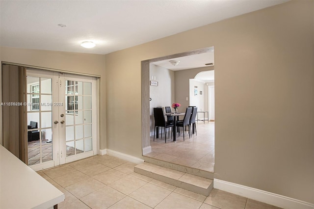 doorway featuring french doors, vaulted ceiling, and light tile patterned floors