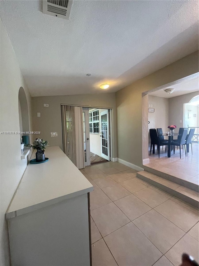 interior space featuring visible vents, light countertops, light tile patterned floors, and a textured ceiling