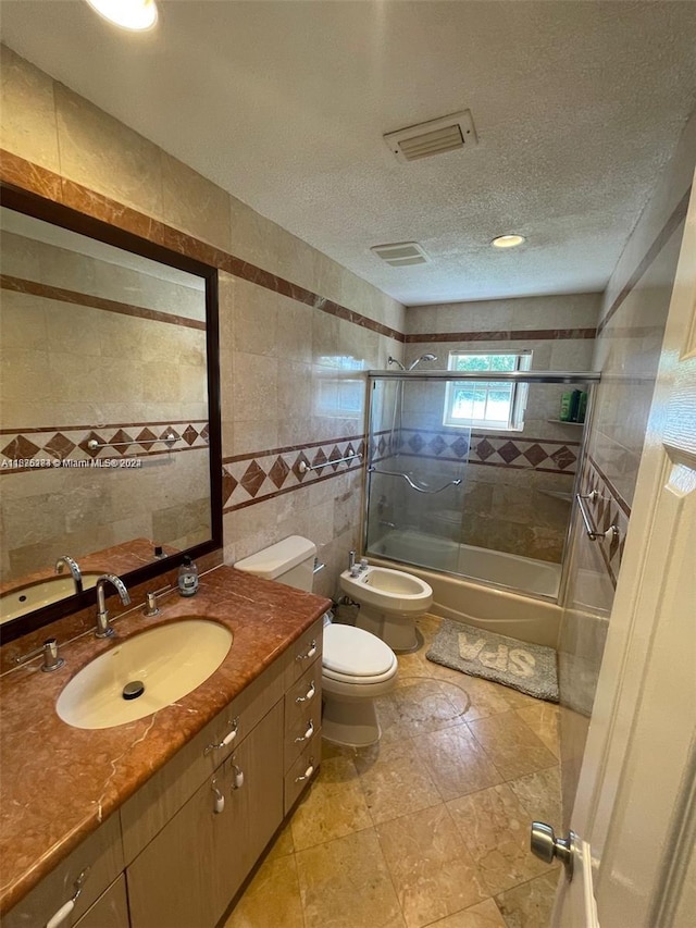 full bathroom with a bidet, tiled shower / bath, vanity, tile walls, and toilet