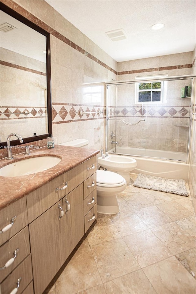 full bathroom with a bidet, shower / bath combination with glass door, vanity, toilet, and tile walls