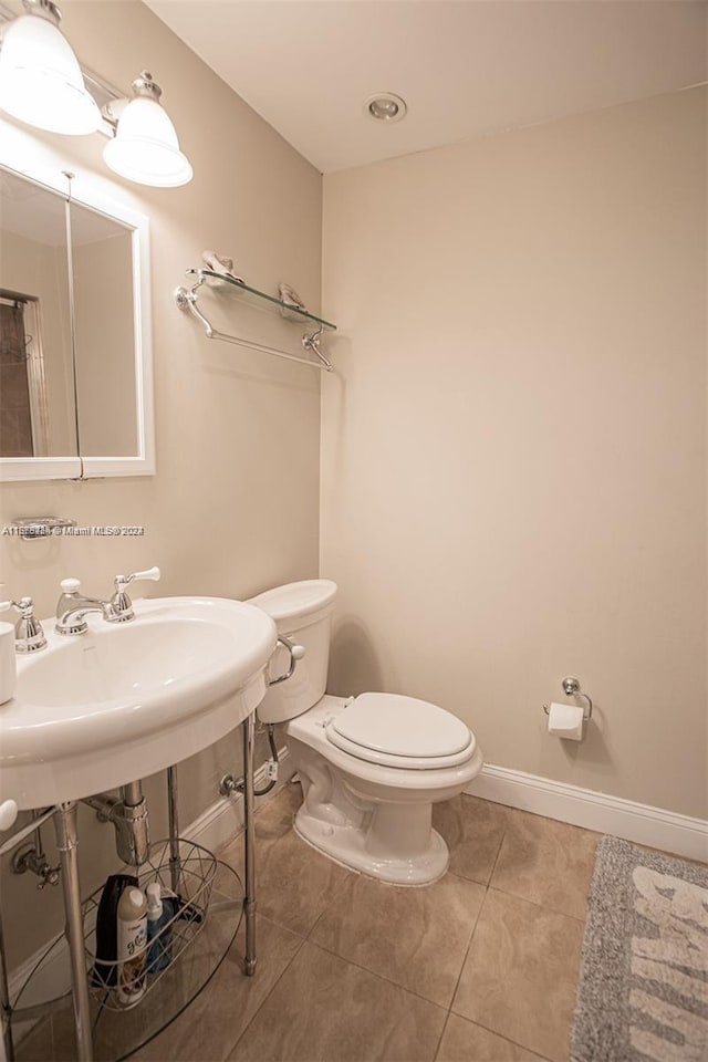 half bath featuring toilet, tile patterned floors, and baseboards