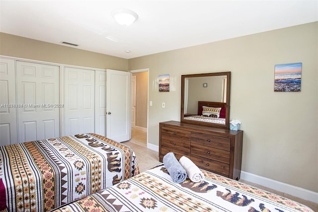 bedroom featuring visible vents, baseboards, a closet, and light tile patterned floors